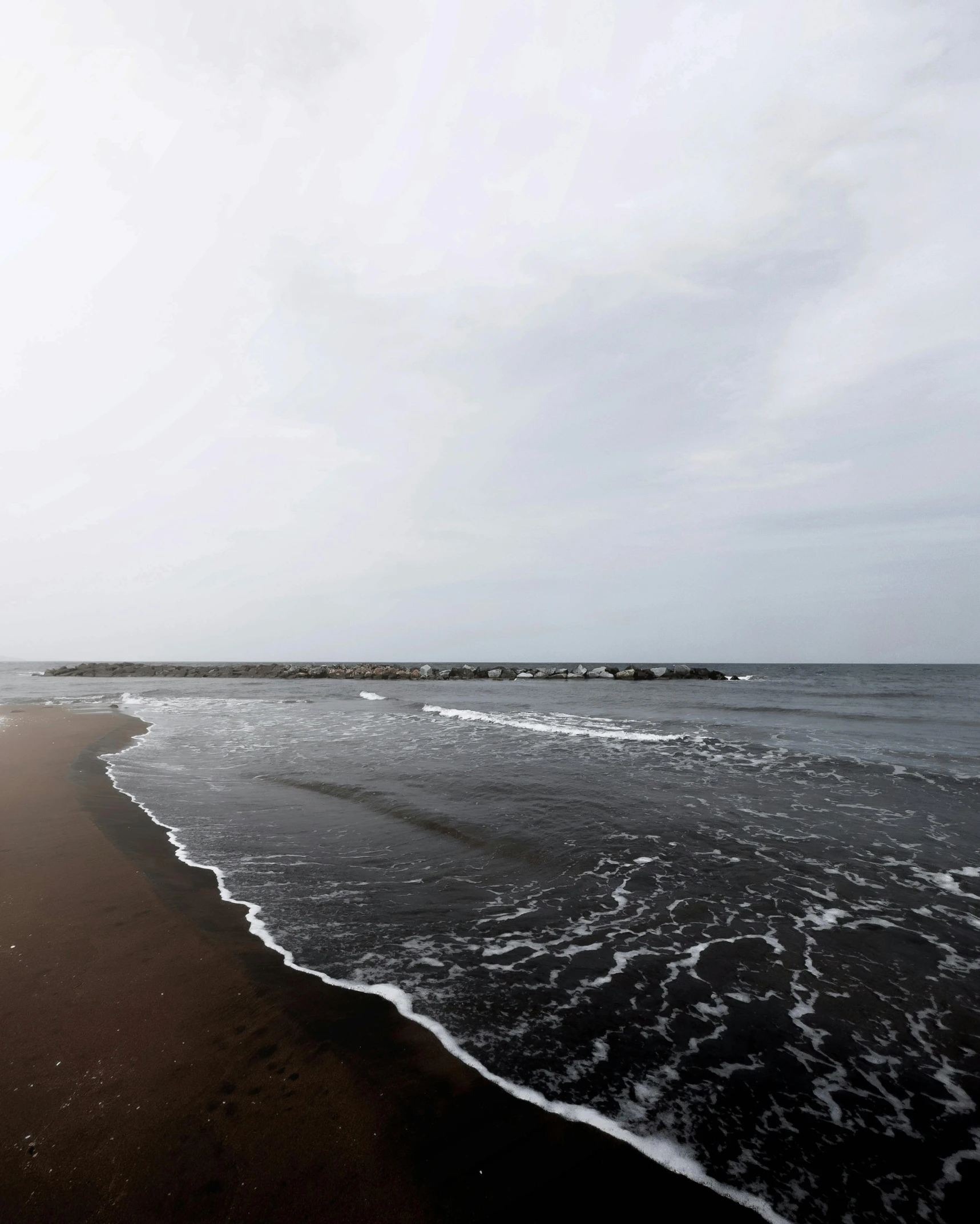 the beach is empty, with some waves coming in