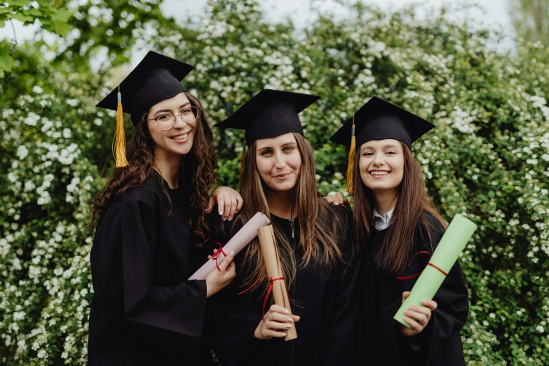 three girls in graduation caps and gowns pose for a picture