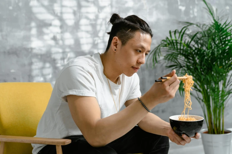 a young man eating ramen noodles from a bowl