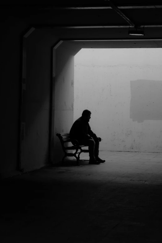 the man is sitting alone in the parking garage