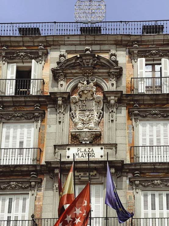 two flags hanging on a balcony next to an apartment building