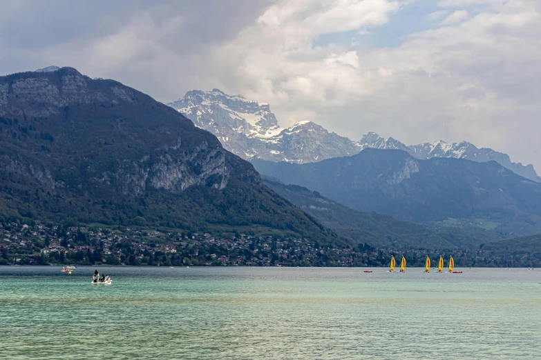 a few sail boats floating in a lake with mountains behind