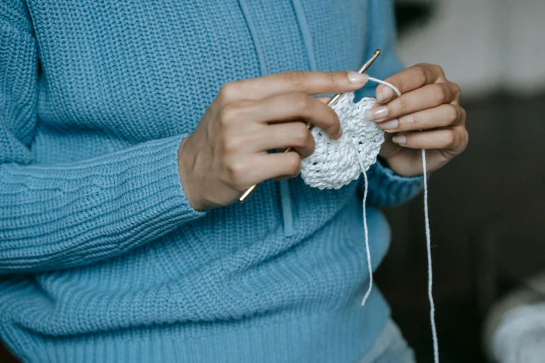 a woman working on knitting with a small crochet stitch