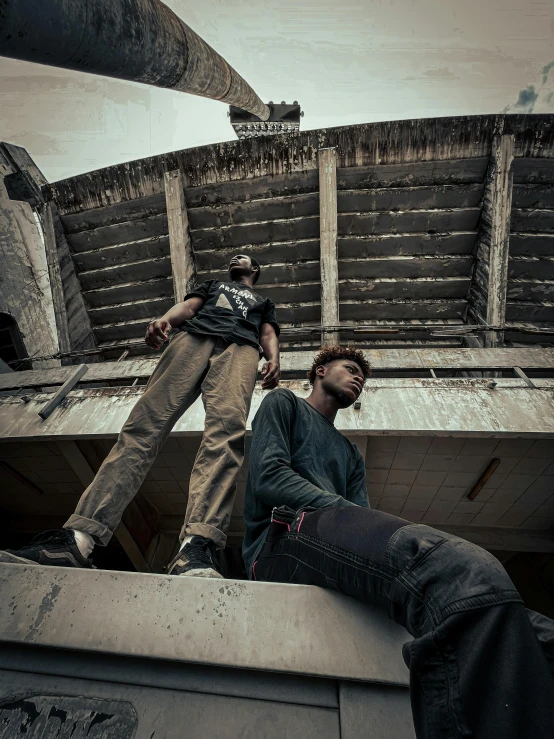 a young man is sitting on a ledge while another one stands by him