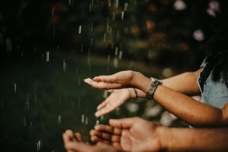 woman with blue shirt standing in rain letting someone dry off