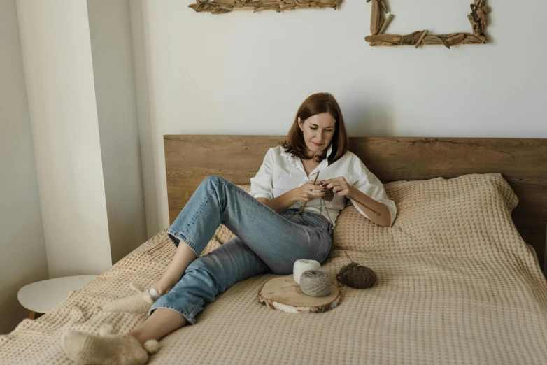 a woman sitting on her bed and checking her cell phone