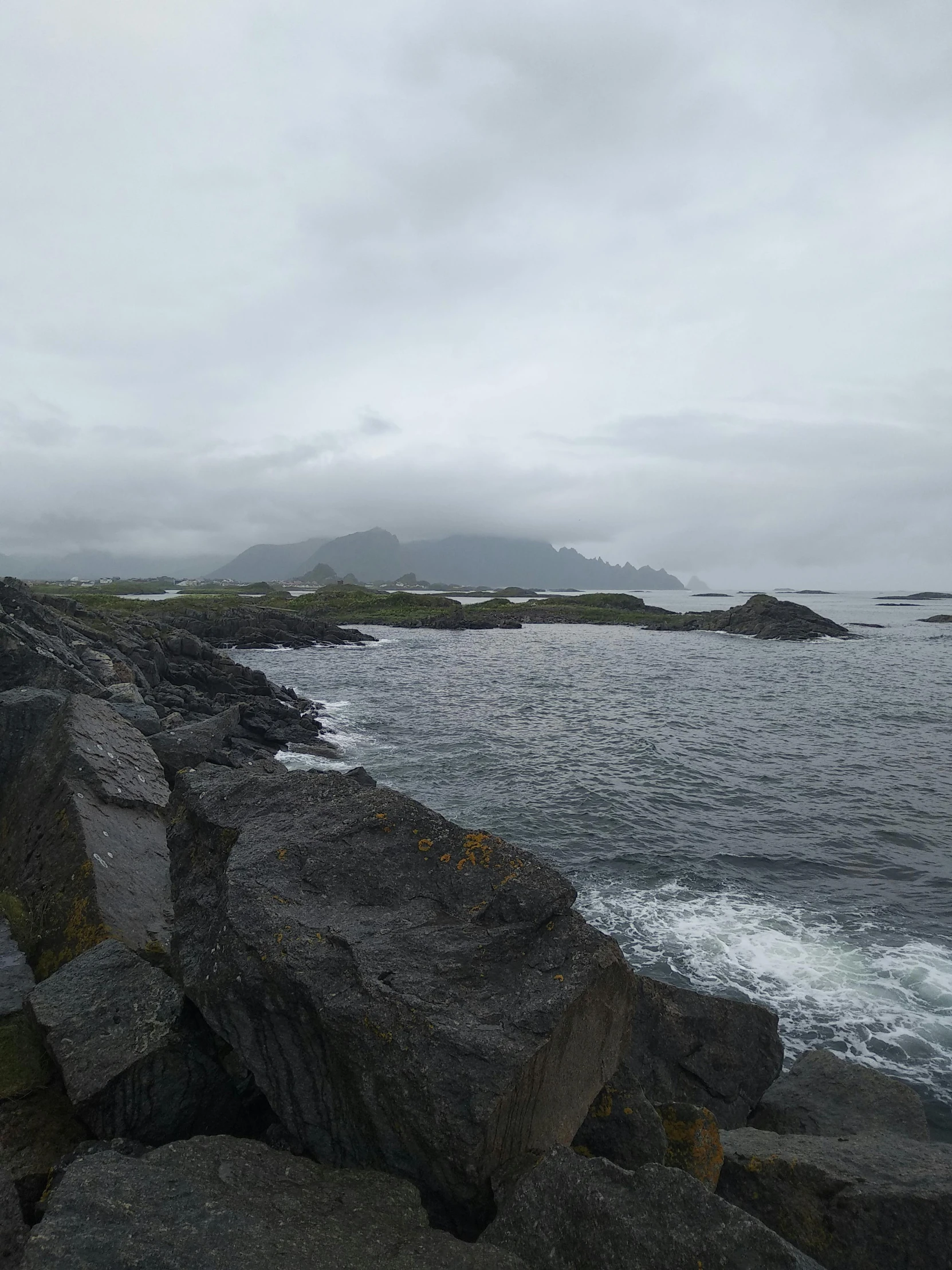 a man is standing on some rocks by the water