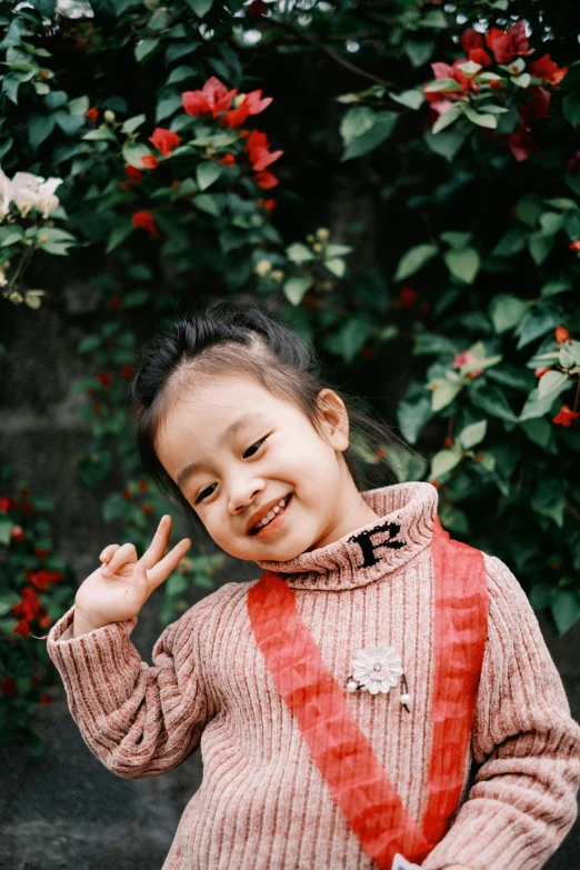 a little girl holding a red ribbon around her neck