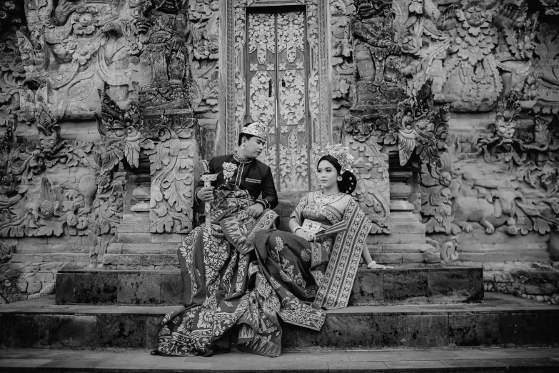 a man and woman sit on steps near a doorway