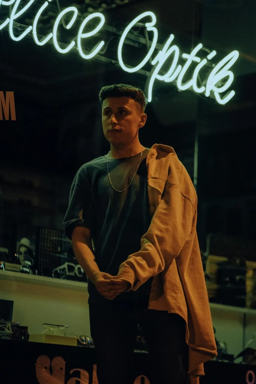 a person in black shirt standing in front of a neon sign