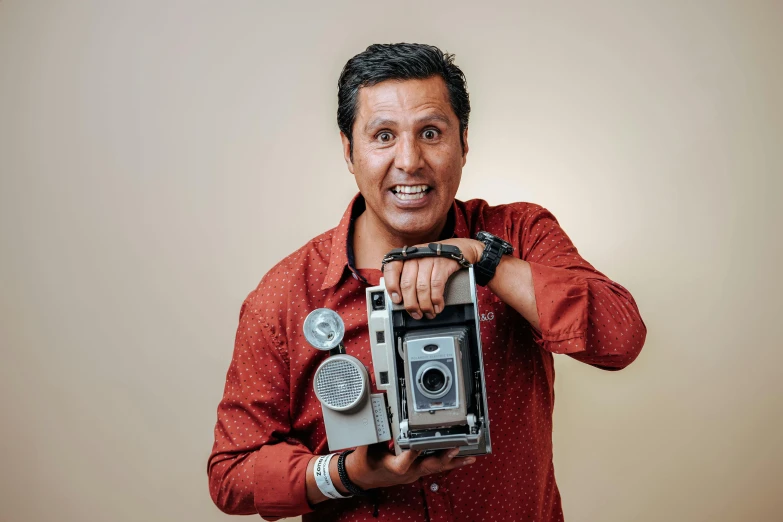 man holding an old camera and smiling