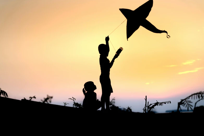 a couple of people standing next to each other while holding onto kites