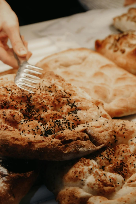 a woman is using a fork to take bread from the baking sheet