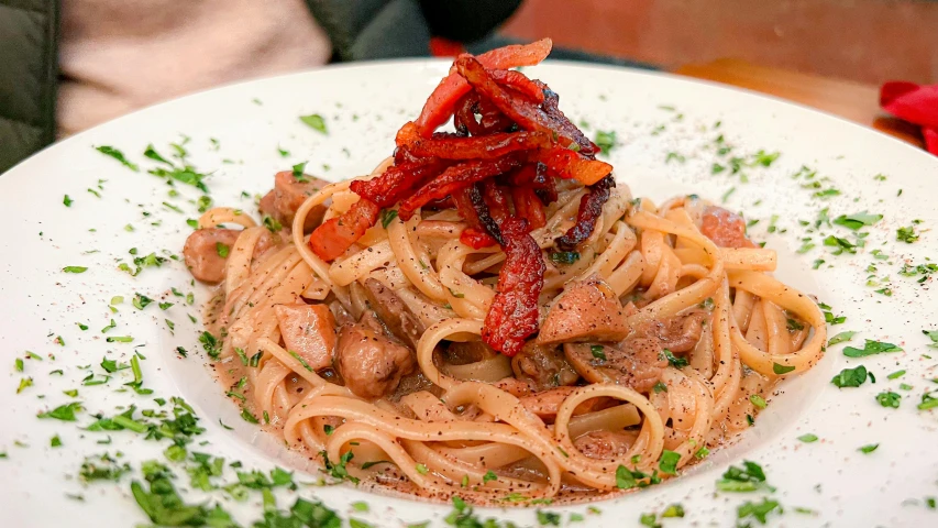 the pasta dish has pepper sprinkles and garnished with red peppers