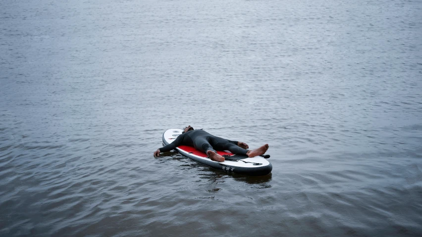 a person on an inflatable kayak with his feet dangling off the handle of the paddle