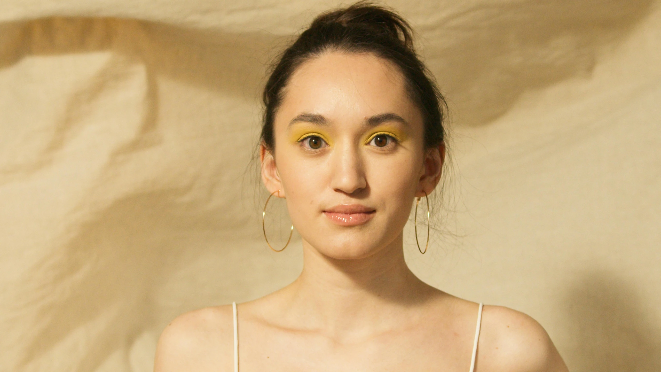 a woman with a yellow eye makeup and hoop earrings on