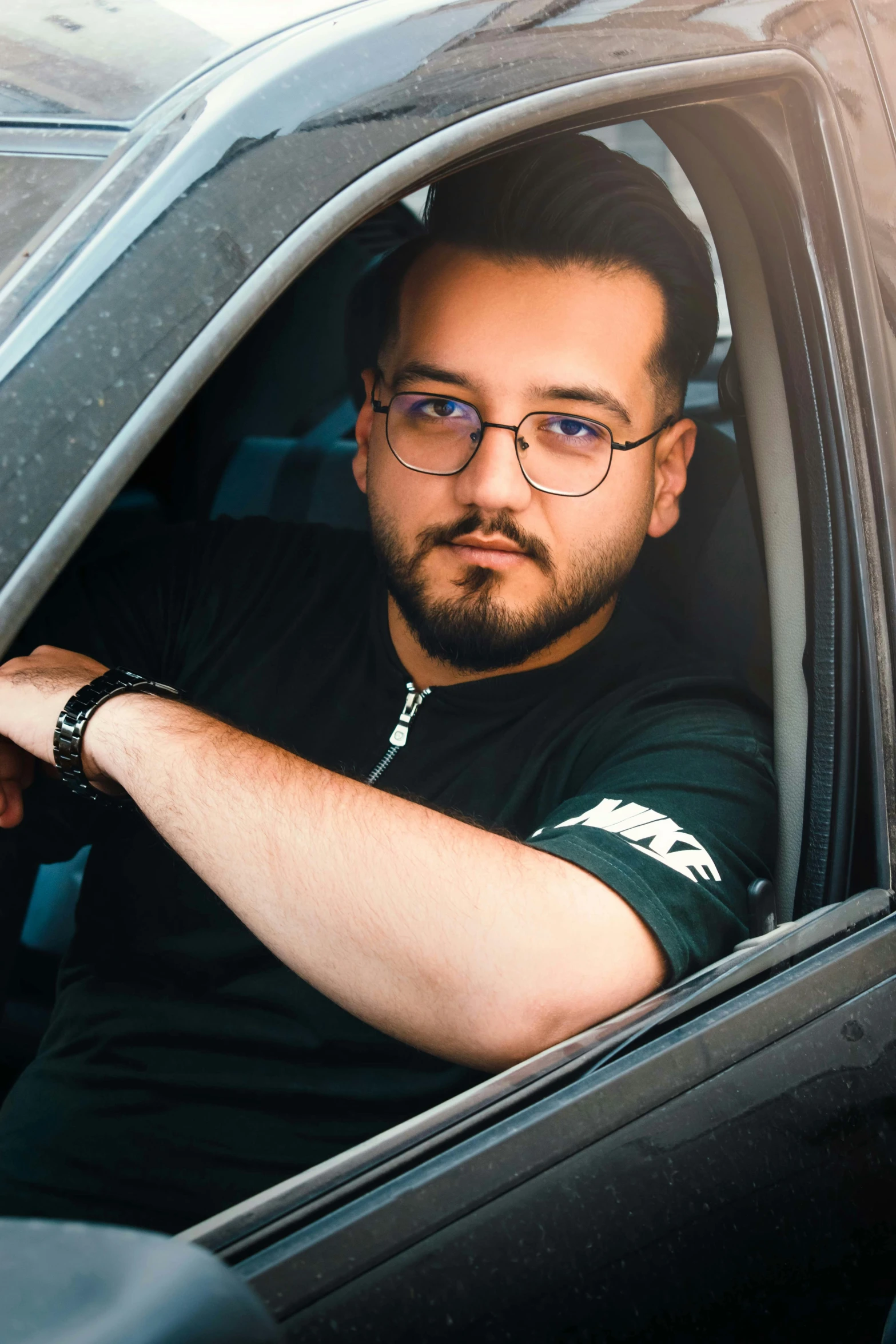 a man is driving a car with his hand on the passenger seat