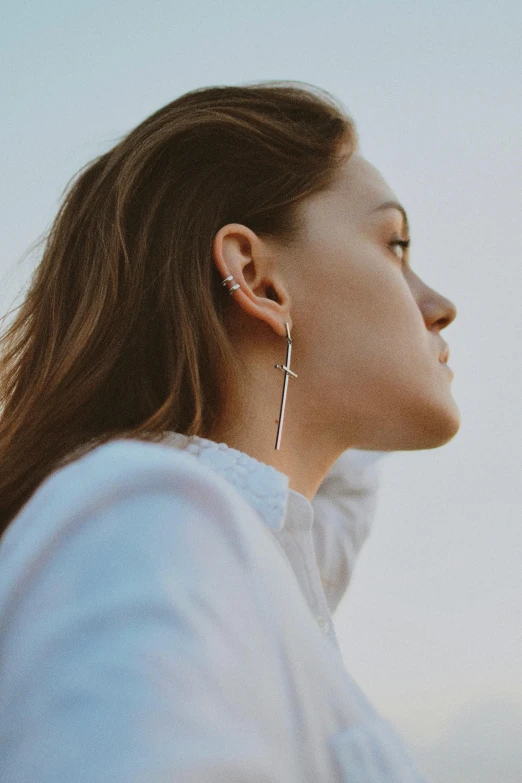 a woman wearing ear rings looks off to the side