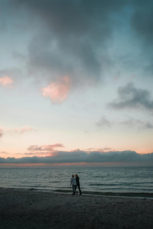 two people standing on a beach with a kite