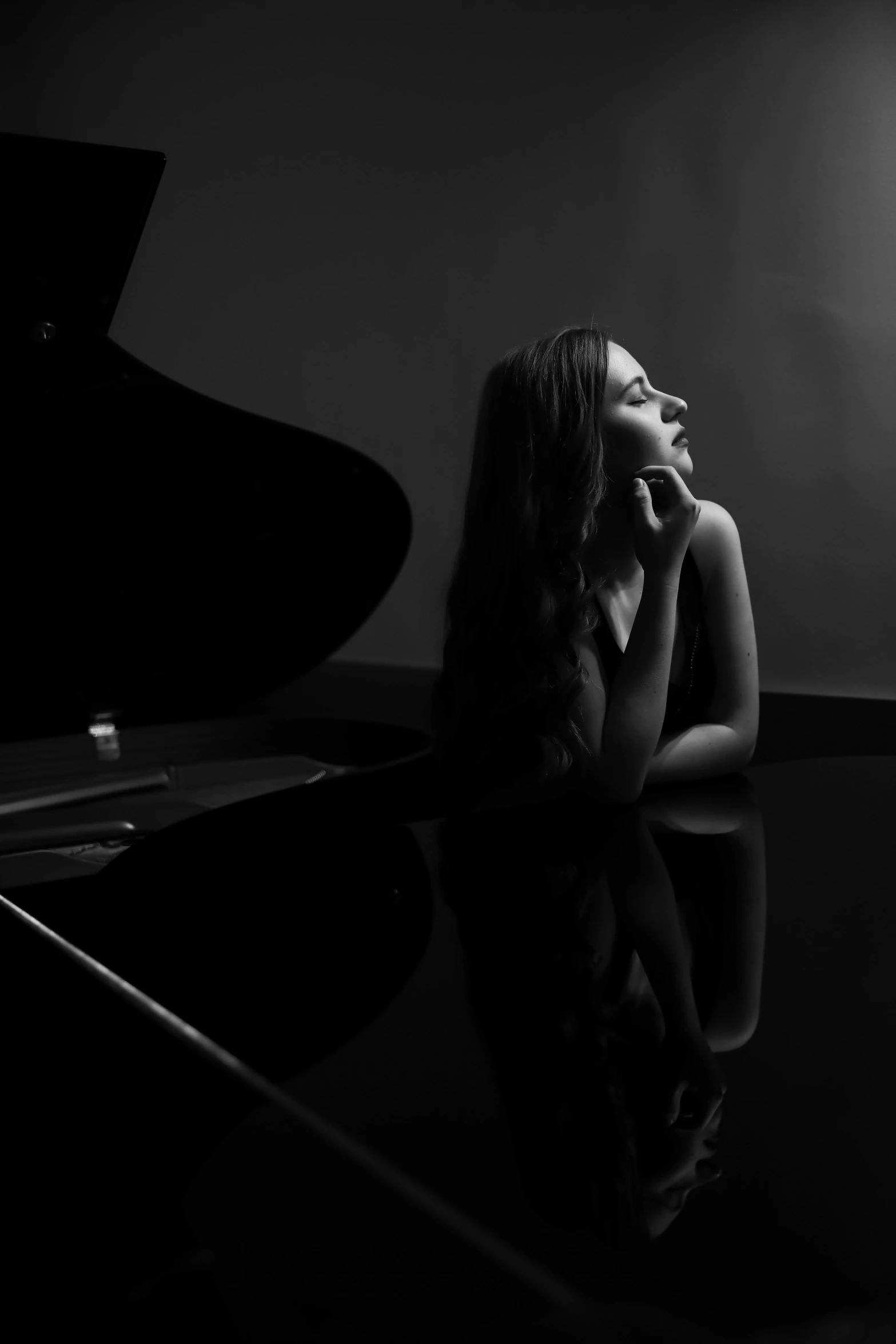 a woman is sitting by a piano in black and white