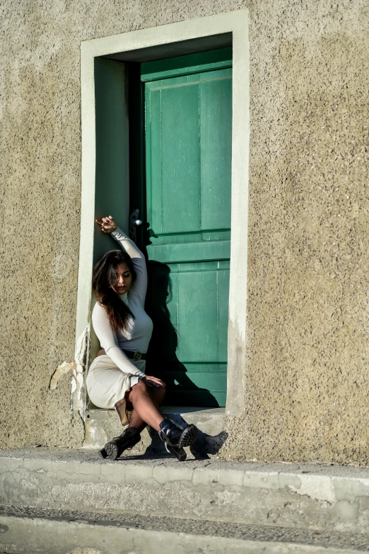 woman leaning against a stone wall in front of a door