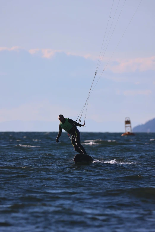 a man kiteboard holding on to wires that hang above the water