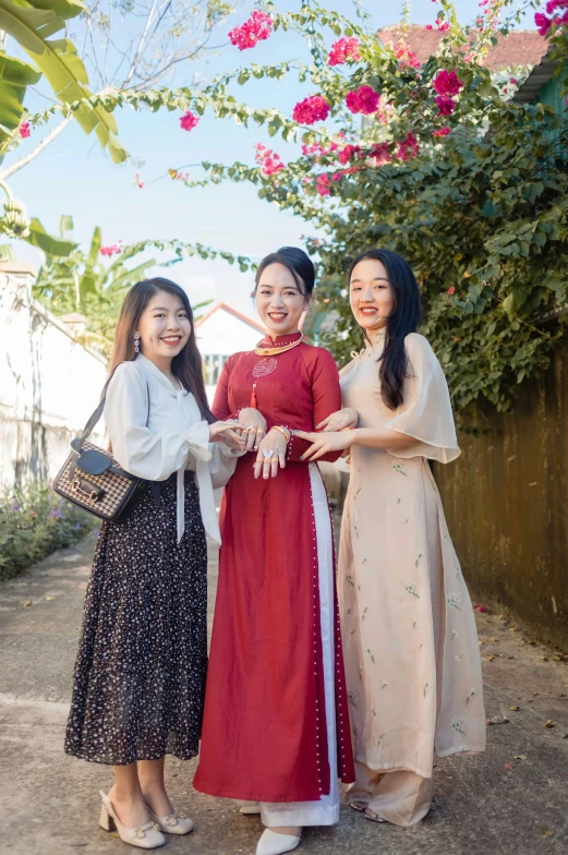 three women smiling and posing in dresses