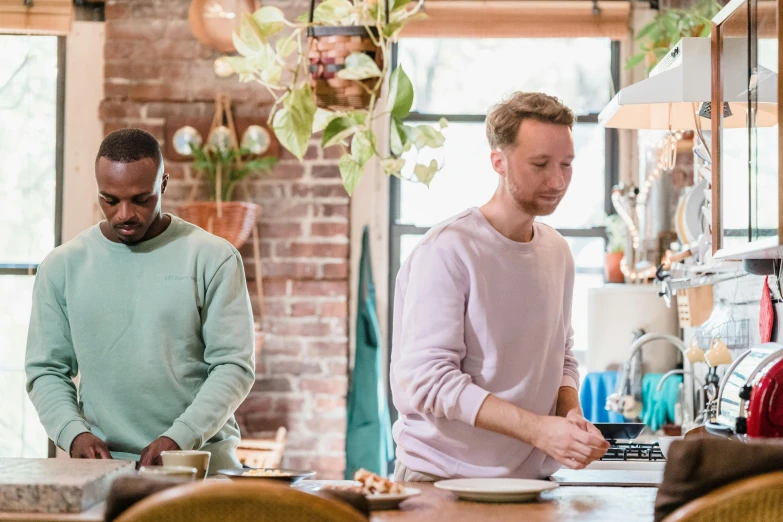 two men standing next to a table with pizzas on it