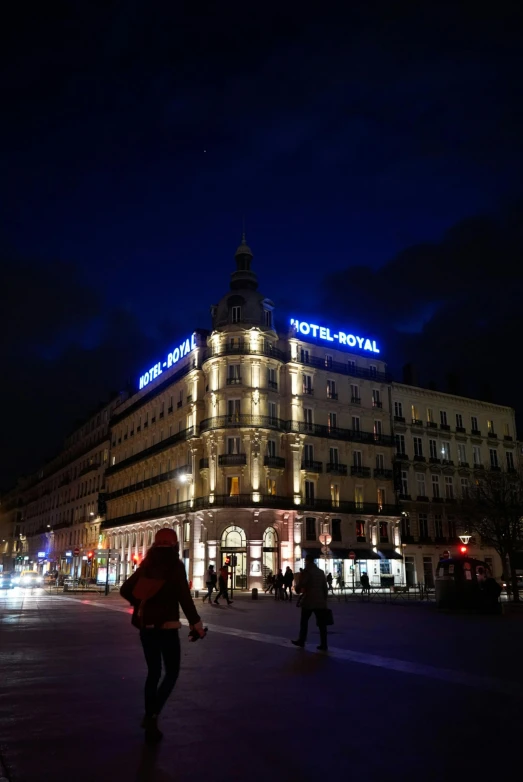 people walk down a road in front of el royal