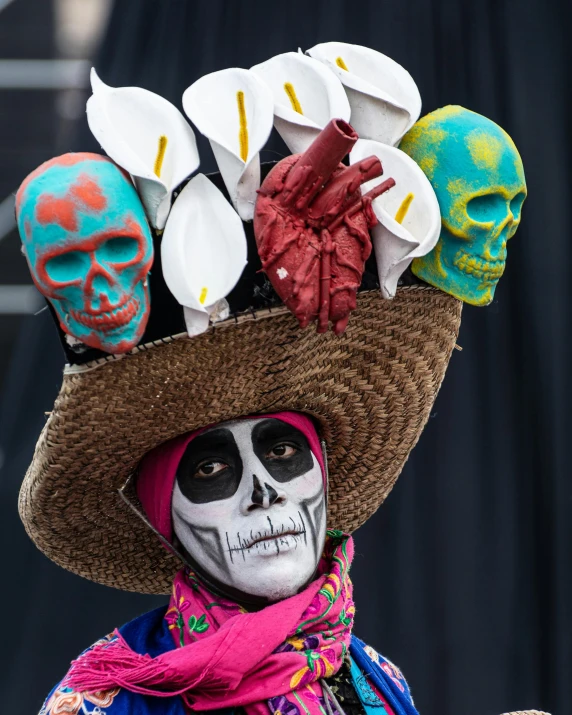 a man in an mexican outfit and skull makeup, with two different colored hats