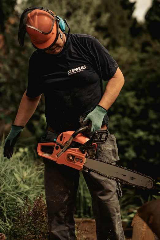 a man wearing a hard hat and sunglasses holding a chainsaw