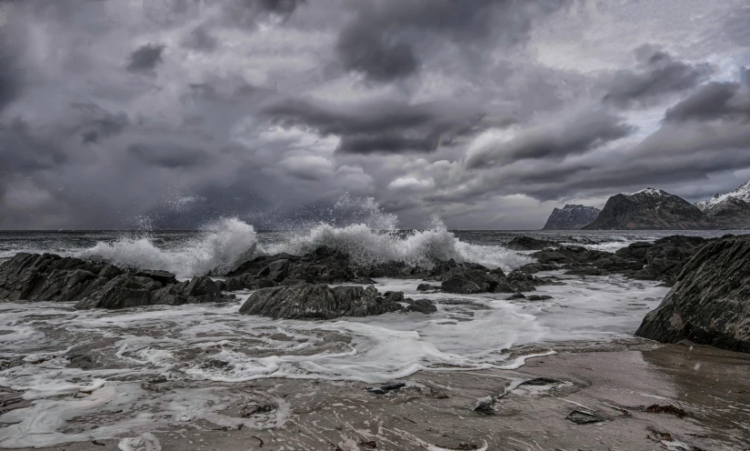 this is an ocean storm with lots of crashing rocks and a mountain in the distance