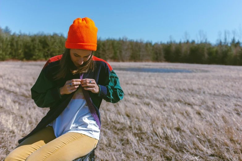 a woman kneeling in a field with a phone