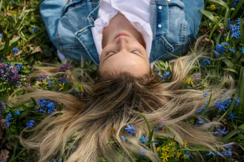 a woman laying in the grass with her hair blowing