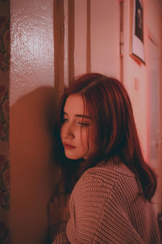 a young woman leans against a wall with her face on the wall