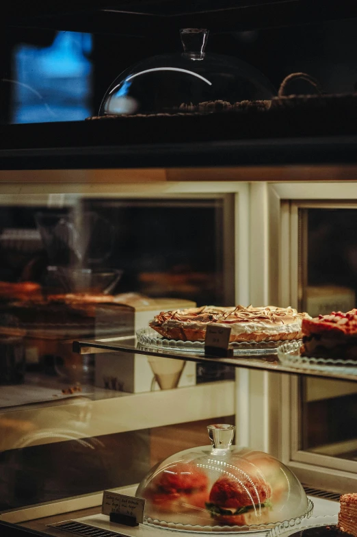 several different kinds of cakes behind a glass window