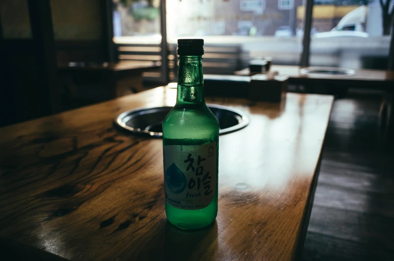 a green bottle sitting on top of a wooden table