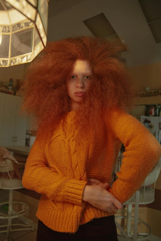 a woman with long red hair wearing an orange sweater