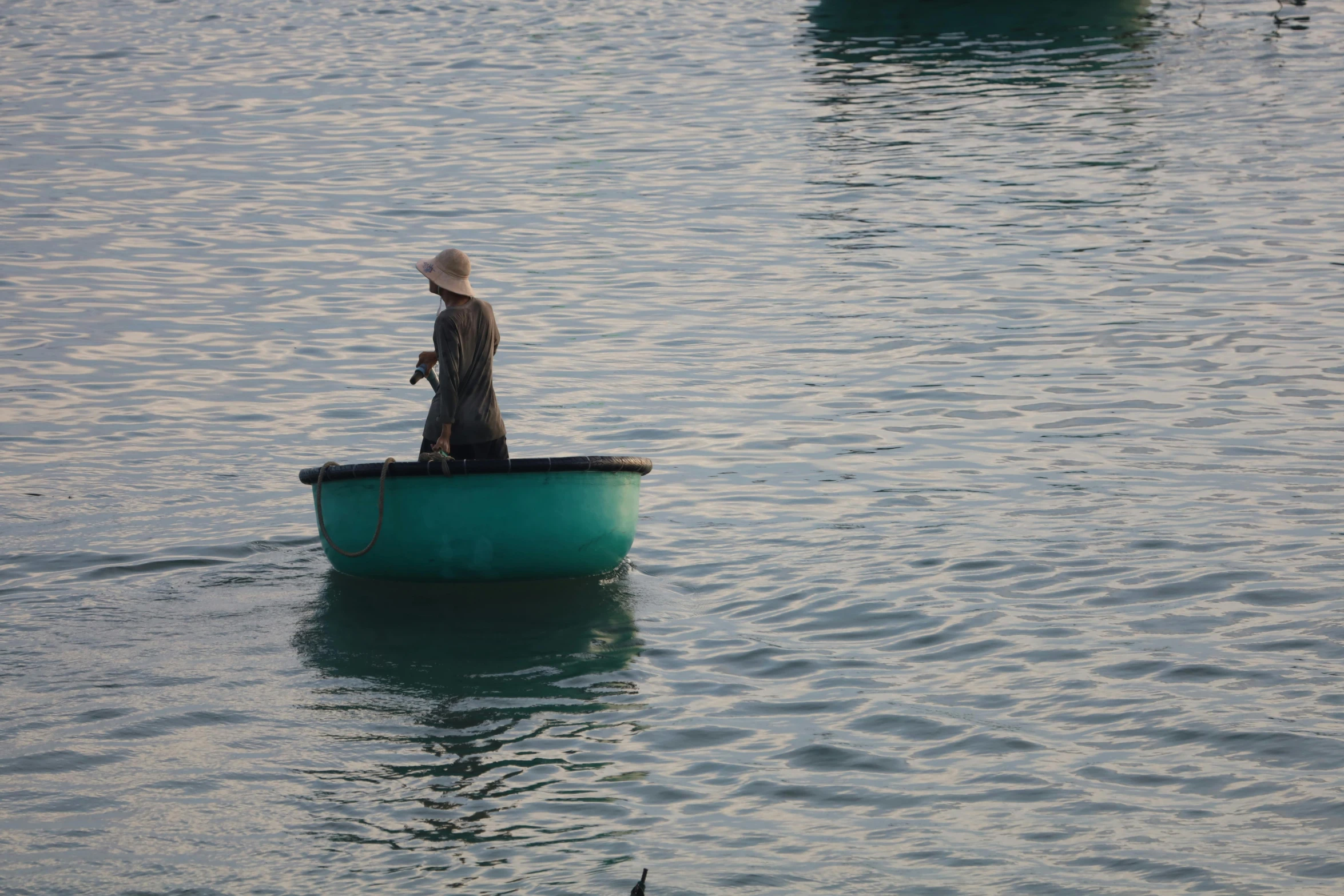 a man stands in the bow of a green boat