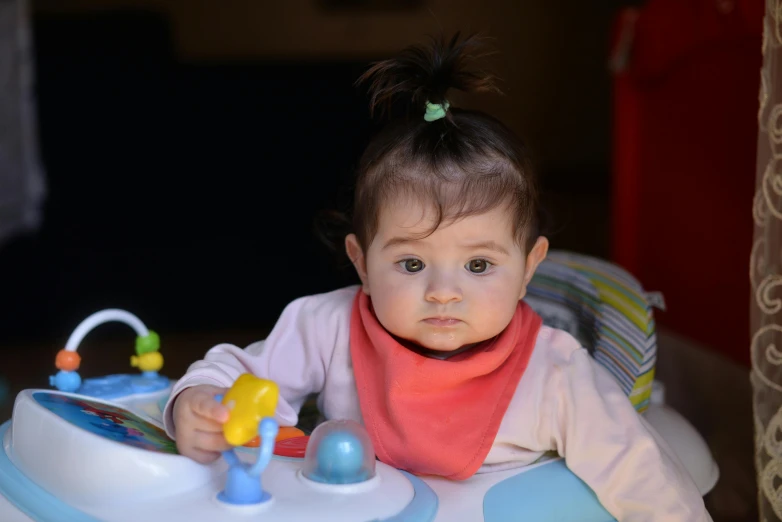 a  sitting in her chair playing with toys