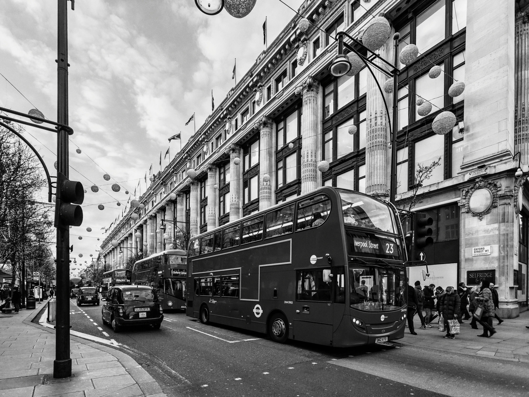 black and white pograph of double decker bus in city