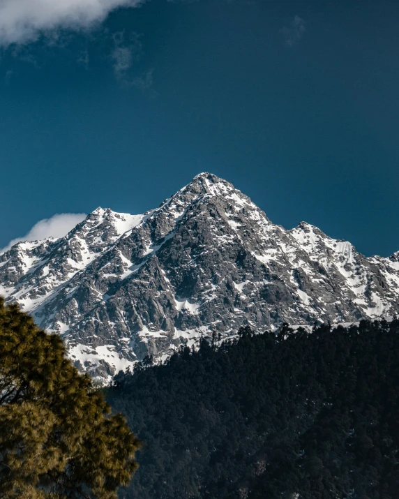 a snow - capped mountain peaks in the distance with a cloud in the sky