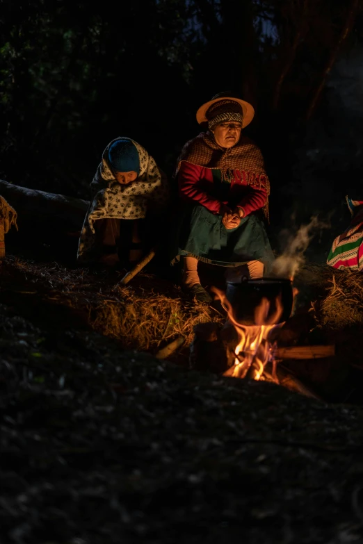 women in colorful clothing standing over a stove with a flame