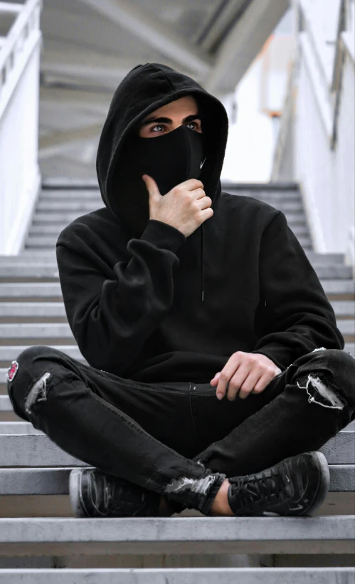 a man with a hooded sweatshirt sitting on some stairs