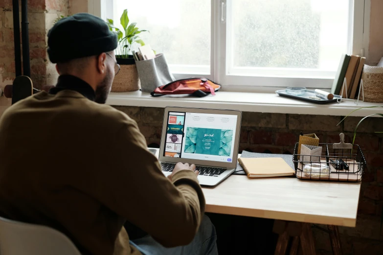 a man is sitting in front of a window with a computer