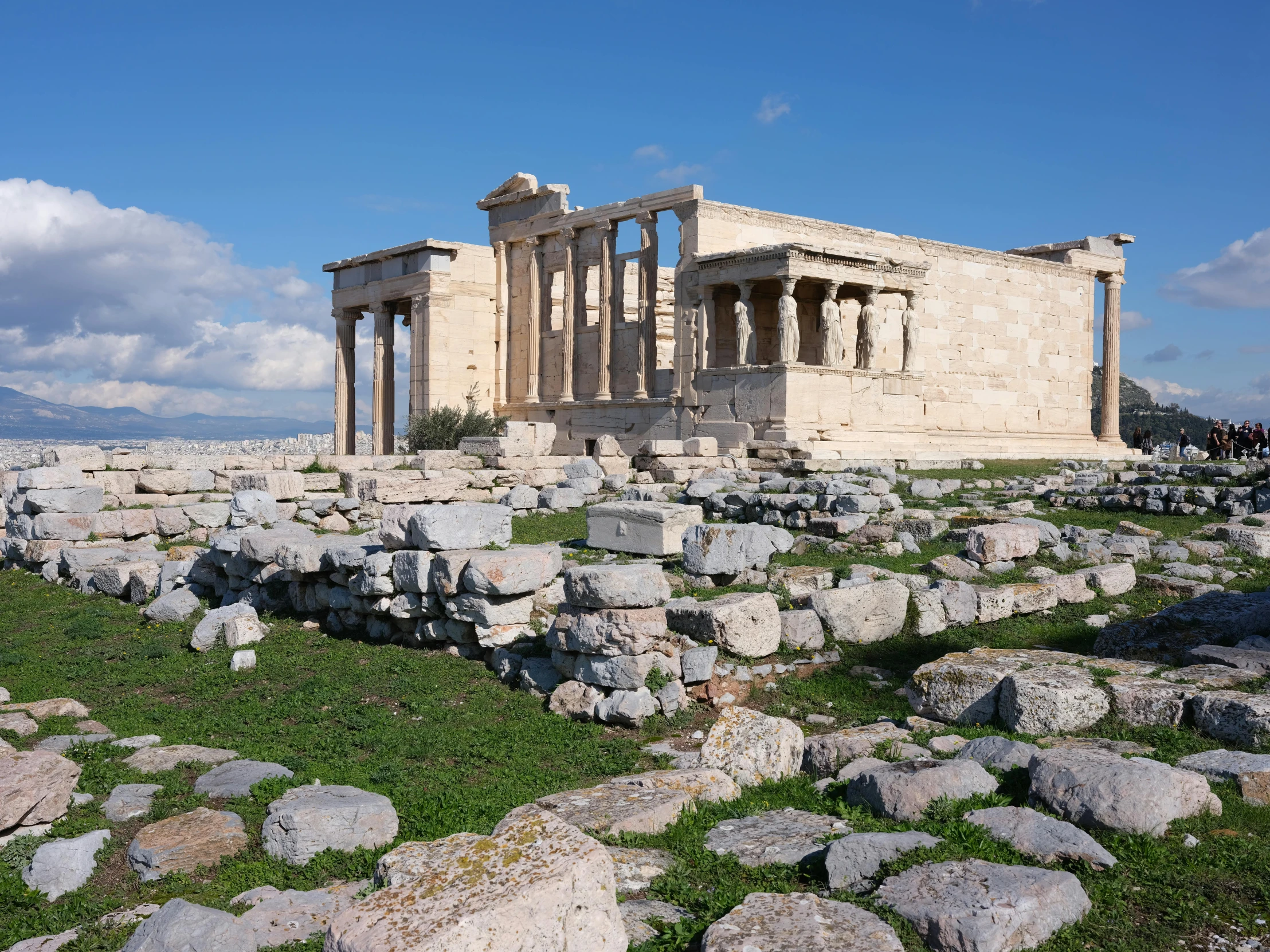 a large building with two columns sits in the middle of some rocks