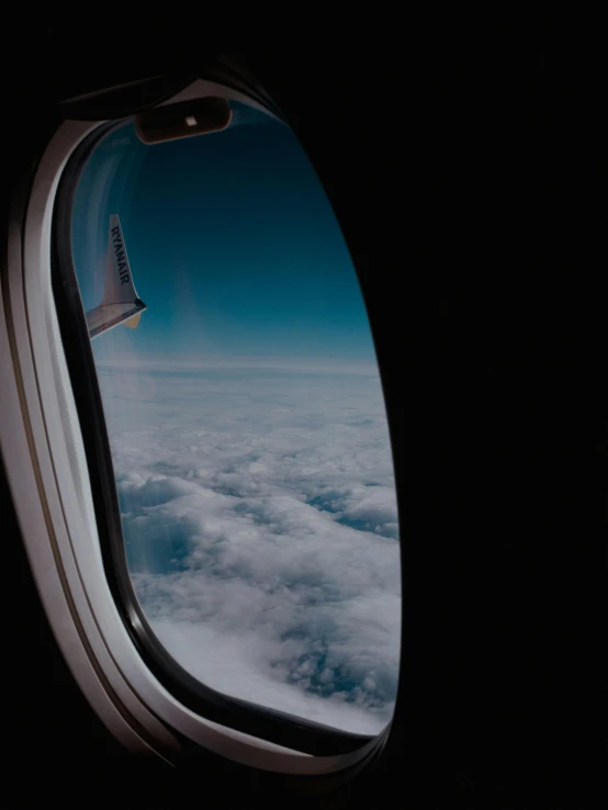 a window with clouds below and the view from inside it