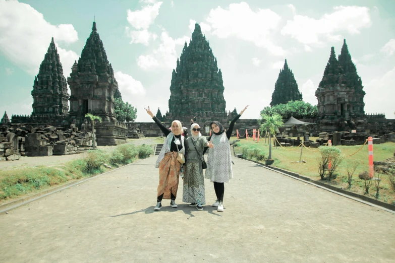 three ladies standing outside of a large building with carved stone towers