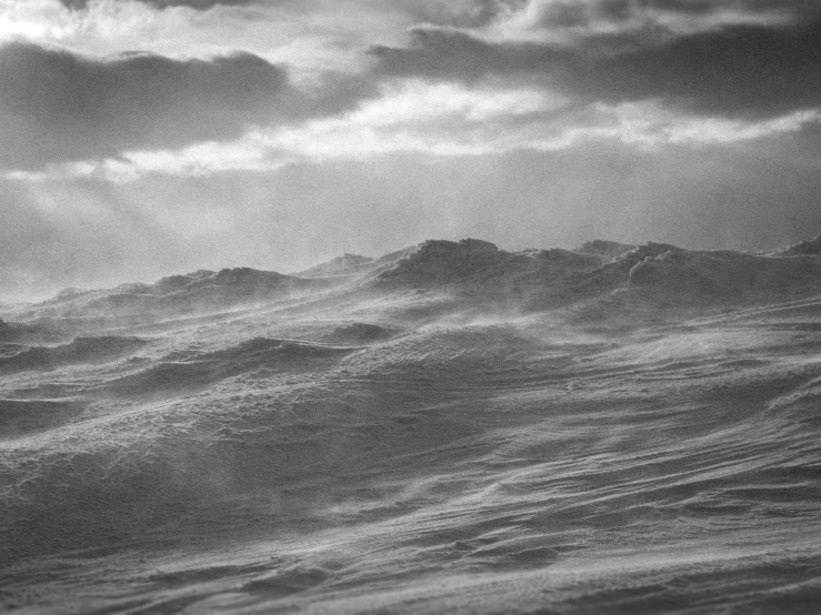 the clouds are over the ocean and in the distance is a large wave