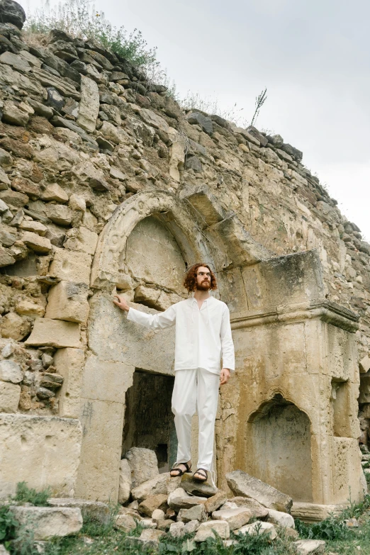 a man in white standing next to a stone structure